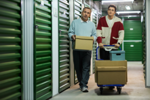 middle-aged-man-teenager-carrying-boxes-storage-facility 1